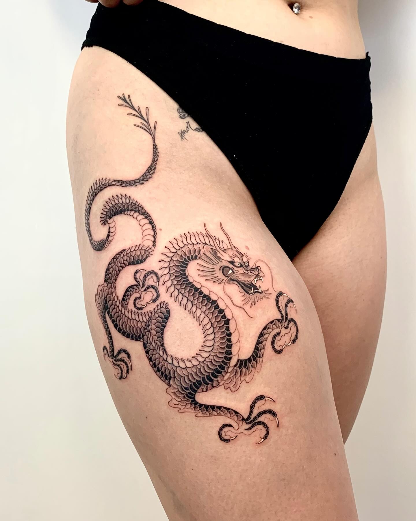 Tatouage dragon lové sur la cuisse